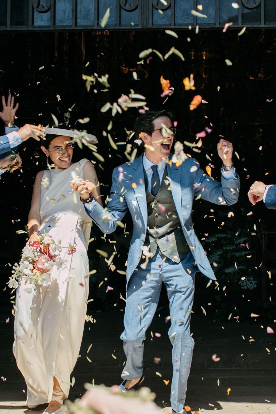 Novios saliendo de la ceremonia entre pétalos en su destination wedding en la Costa Brava, publicada en Vogue