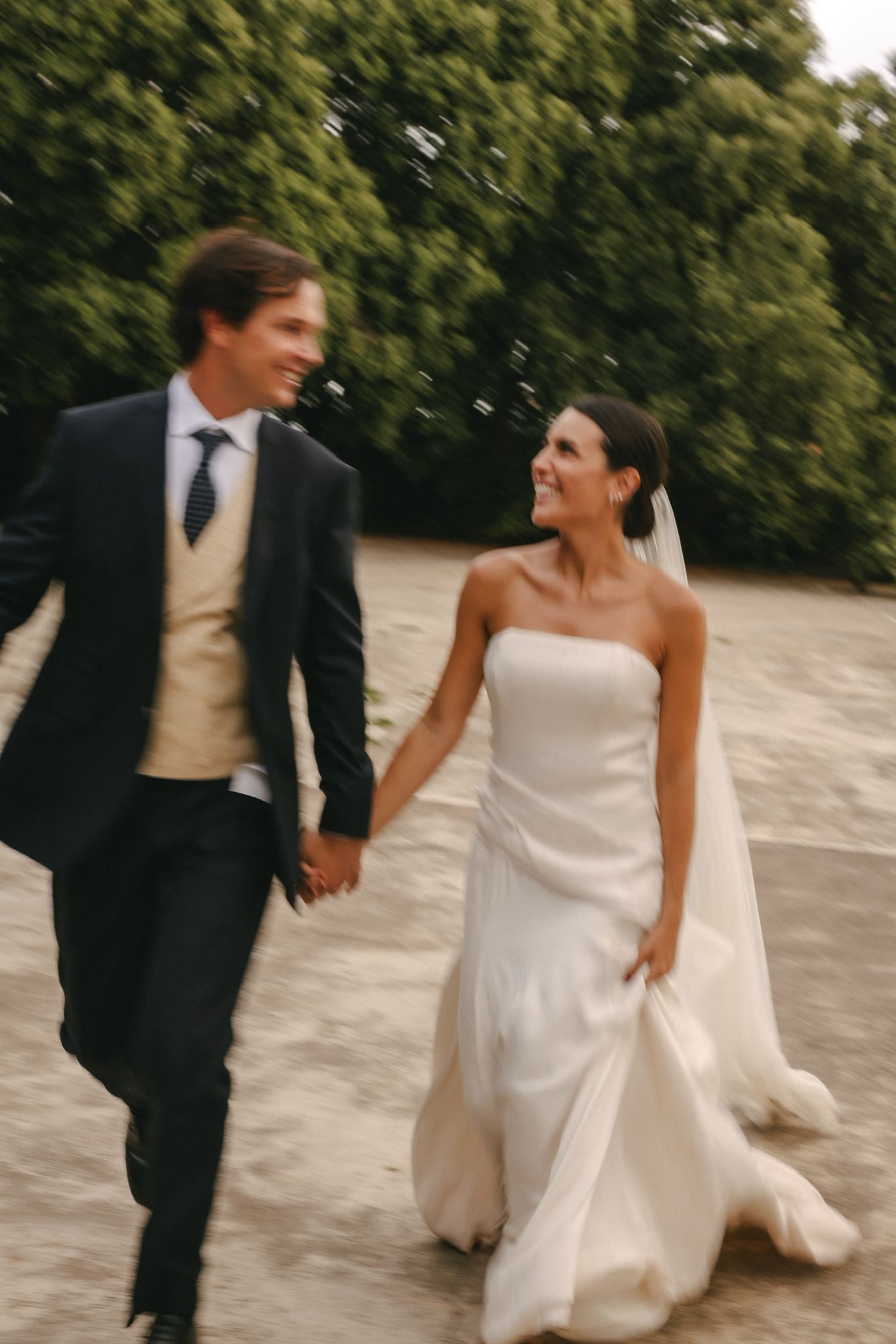Novios caminando de la mano entre pinos el día de su boda