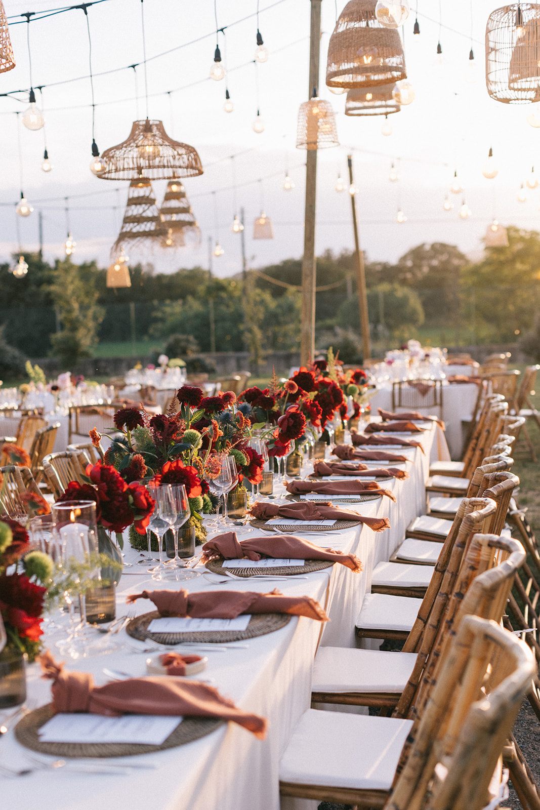 Mesa larga decorada con velas y flores para una boda al aire libre