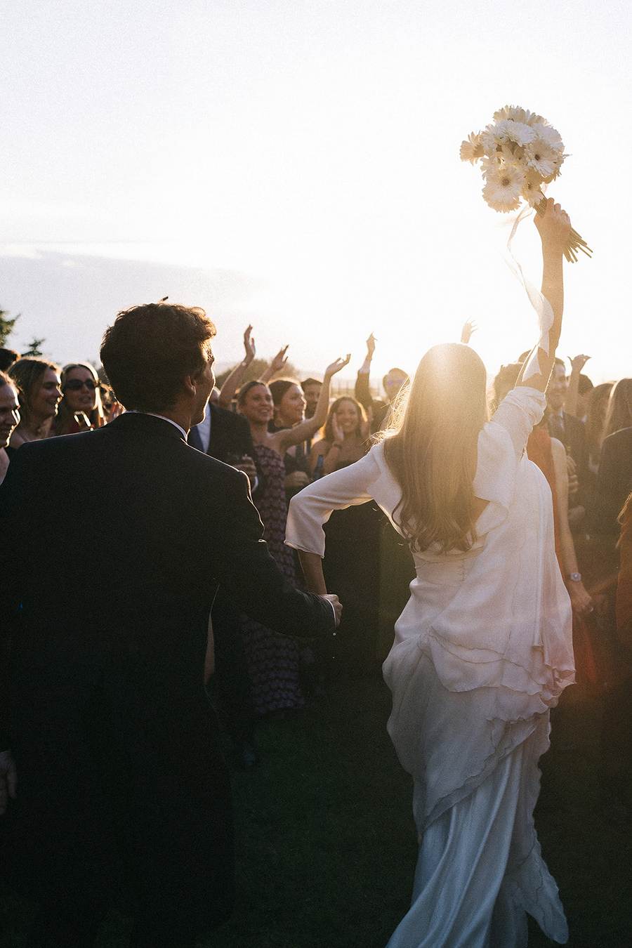 Invitados celebrando y lanzando pétalos a la pareja de novios