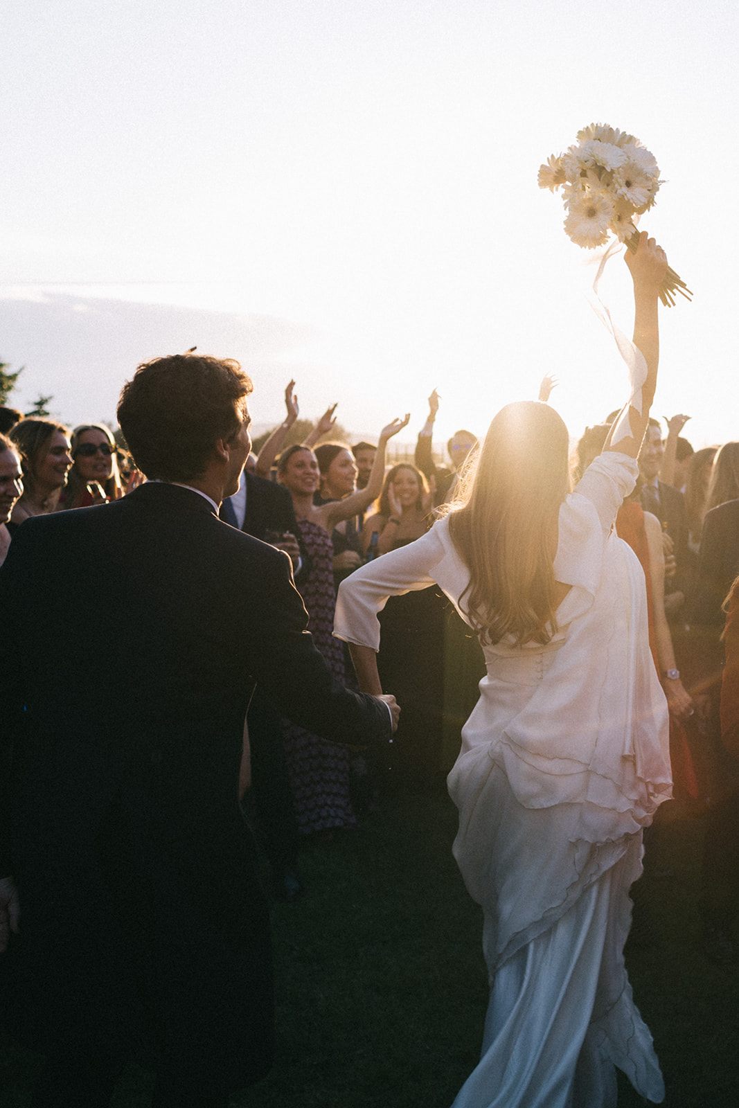 Invitados celebrando y lanzando pétalos a la pareja de novios