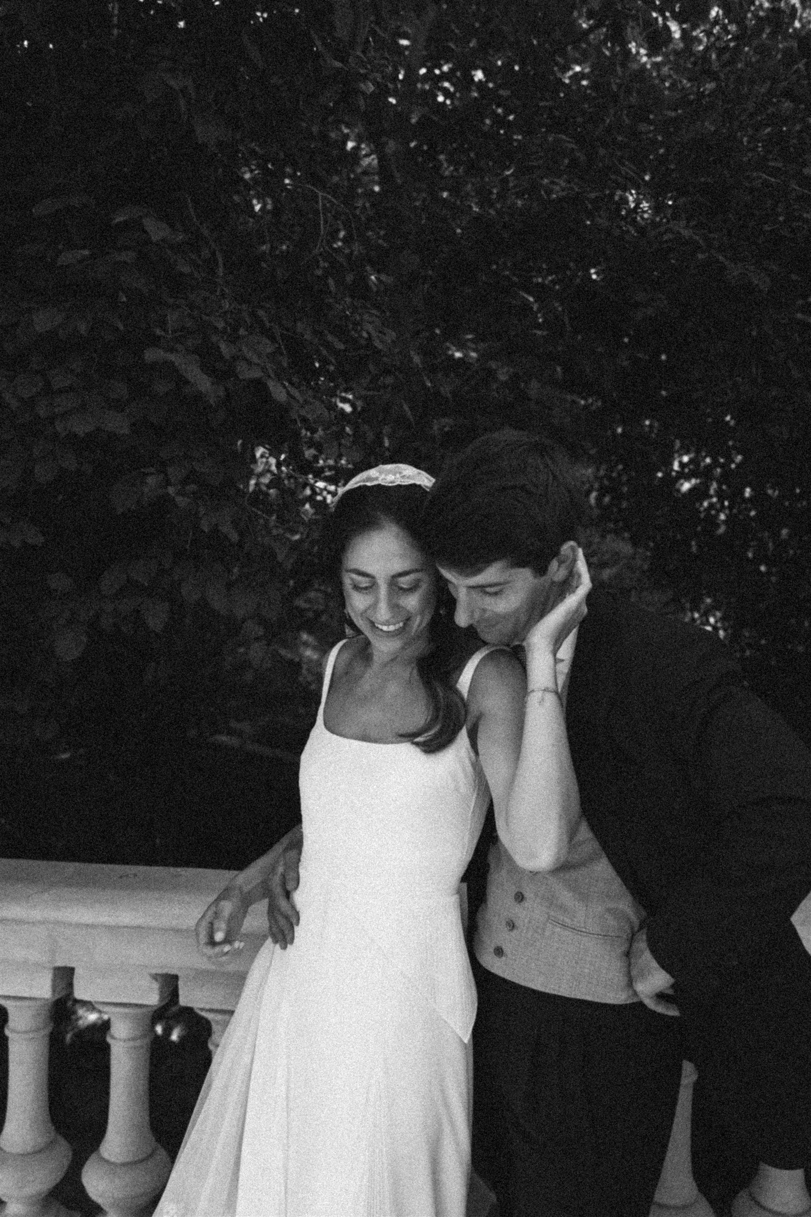 Pareja de novios sonriendo en la escalera de una masía durante la coordinación de su boda